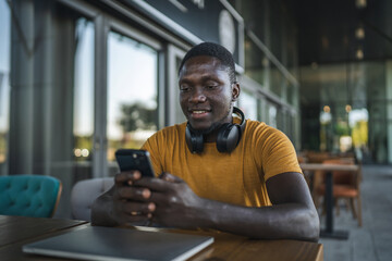 Obraz premium Freelancer enjoying smart phone during work break at outdoor cafe