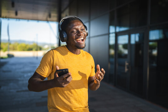 Young man listening to music with headphones and smart phone is dancing and singing