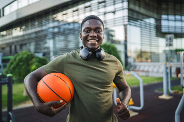 Young african american sportsman holding basketball ball in outdoor gym