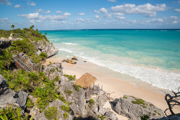 Turquoise Caribbean waters and tropical plants overlooking sandy beach in Tulum, Mexico.