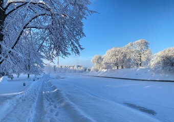 Obraz premium A picturesque winter landscape in Parnu, Estonia with a snow-covered path running along a riverbank