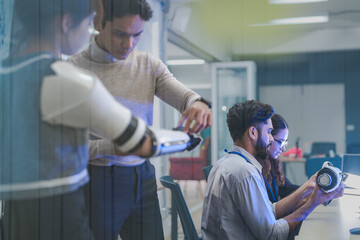 A robotics team develops a new bionic limb, inspecting the prototype while analyzing real-time performance data. A concept for digital twins, agile R&D, and mechatronics innovation.