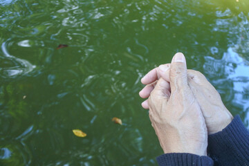 hands together above the pool give the impression of contemplation, the shadow of the image on the surface of the water appears faint
