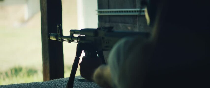 Woman fires rifle during live shooting exercise at outdoor range under supervision