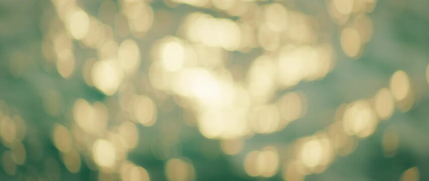 Sun glistening on soft waves with bokeh pattern on sea surface in warm morning