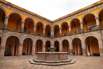 Fototapeta premium Colonial courtyard with central fountain and arched galleries in former monastery in Queretaro, Mexico