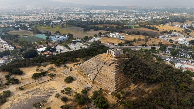 Aerial drone view of El Cerrito archaeological site with pyramid and surrounding urban landscape in Queretaro, Mexico