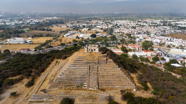 Aerial drone view of El Cerrito archaeological site with pyramid and surrounding urban landscape in Queretaro, Mexico