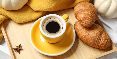 Cup of tasty pumpkin coffee with croissants and warm plaid on bed at home