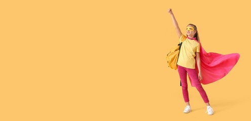 Little schoolgirl dressed as superhero on yellow background with space for text