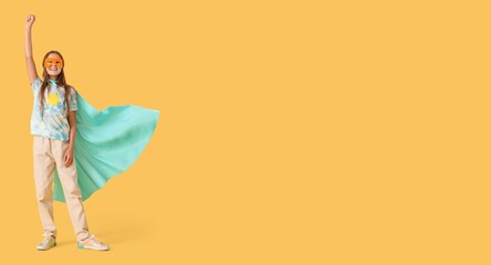 Happy little girl dressed as superhero on yellow background with space for text