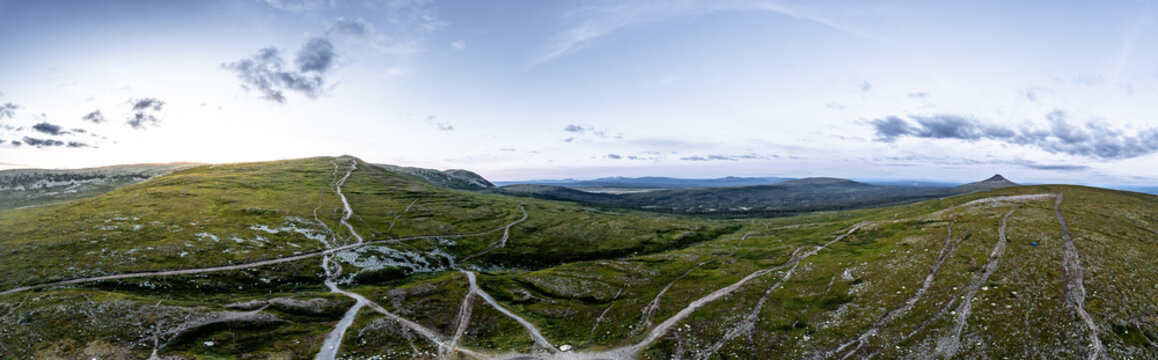 Panoramic aerial view of the vast green tundra landscape under a blue evening sky, showcasing hiking trails winding through the serene St&auml;djan-Nipfj&auml;llet nature reserve Idre Dalarna Sweden