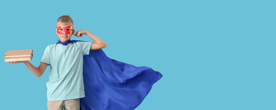 Schoolboy dressed as superhero with books on blue background with space for text