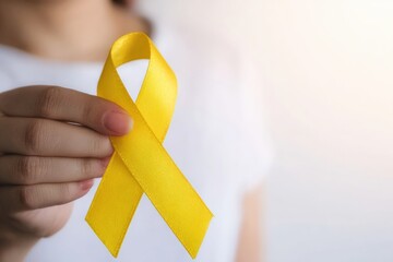 Woman showing yellow ribbon, symbol of support for bone cancer, suicide prevention, endometriosis and bladder cancer awareness