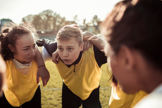 Teen soccer team huddling before match on outdoor field