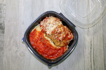 Eggplant parmesan and spaghetti in a to go container ordered online for curbside pick-up during coronavirus pandemic.