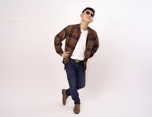 Naklejka premium Man in plaid shirt and sunglasses poses stylishly for casual fashion concepts on white background