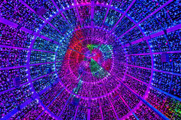 Interior view from below of a cylindrical Christmas tree structure with purple and pink lights forming a tunnel-like pattern