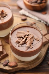 Delicious panna cotta with chocolate and cocoa beans on wooden table, closeup