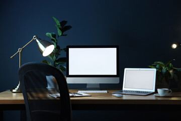 Stylish workplace with modern computer, laptop and stationery on wooden table in office
