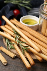 Delicious grissini sticks and rosemary on wooden table, closeup
