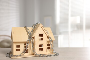 Fototapeta na wymiar Home security. House model with chain on wooden table indoors, space for text