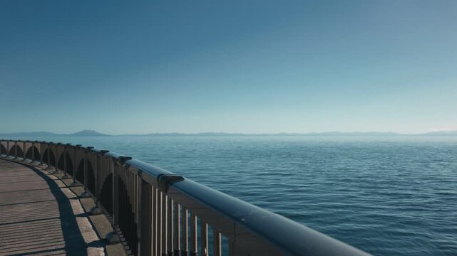 グラデーションの美しい空と遠い岬の見えるカーブする海上デッキ