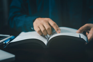 Man is sitting at the table and reading a book, close up, old style. Hand open book for reading. Man is flipping the pages of a book. Learning concept. Teacher.