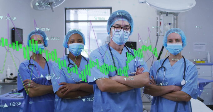 Standing medical team wearing scrubs masks and stethoscopes in surgical suite, with data overlay - Powered by Adobe