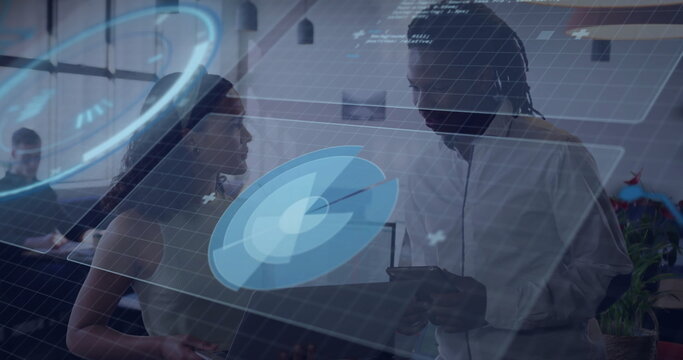 Examining holographic data charts, business professionals discussing trends in office with tablet