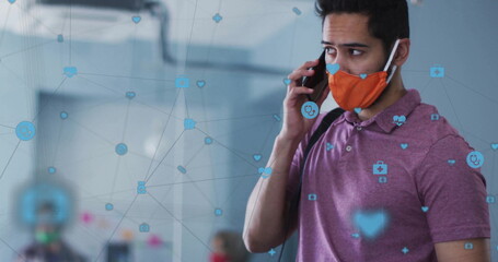 Man wearing face mask and polo-shirt talking on smartphone in lobby, with icon overlays, copy space