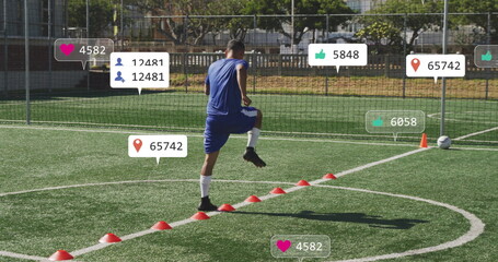 Performing soccer player executing agility drill on artificial turf, with red cones ball net fence