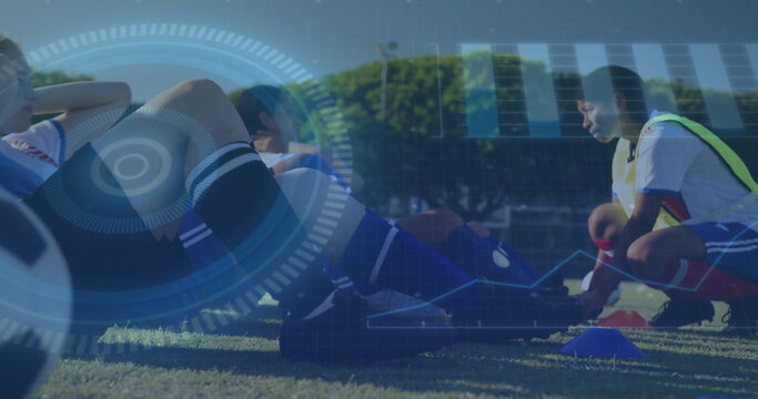 Kneeling female soccer player tying cleat in bib on soccer field, with soccer ball and cones