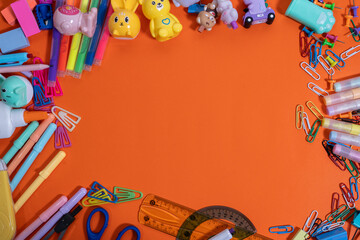 Colorful school supplies framing orange background for back to school season
