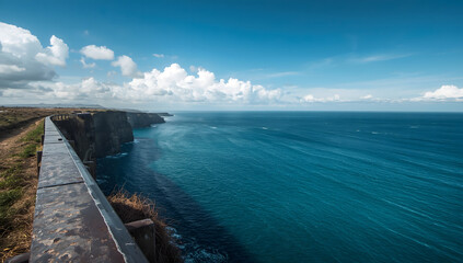 Obraz premium Coastal cliffs meet the vast ocean under a vibrant sky.