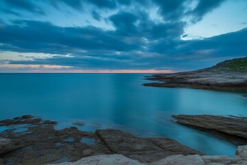 Fototapeta premium Serene coastal landscape at dusk with dramatic clouds over calm ocean water