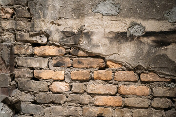 A detailed view of an old brick wall with noticeable cracks and weathered texture, showcasing urban decay and industrial aesthetics.