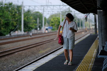A woman walks alone on a train station platform with a sling bag over her shoulder
