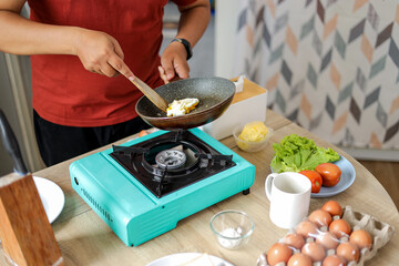 Hands of Man Stirring Scrambled Eggs in Pan on Portable Stove