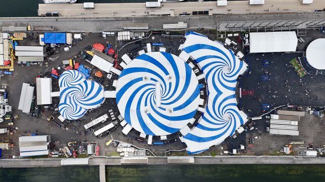 24th of August 2025 drone flight above the Cirque du Soleil blue-white tent at Montreal Old Port with city skyline in background. g.