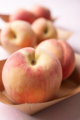 Fresh peaches in paper bowl on pink background, Summer fruit