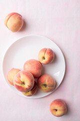 Fresh peaches on white plate with pink background, Summer fruit, Top view