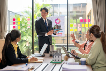 Real estate agent showing house model to investors during presentation meeting