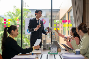 Architects discussing project with miniature model house in office meeting