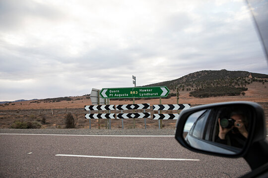 A road sign pointing the way in the outback, with a car mirror reflection