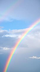 A vibrant rainbow arches across a clear blue sky.