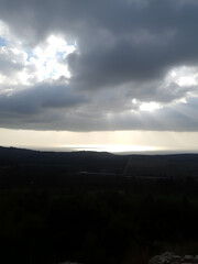 Sun rays shining through rainclouds showing the falling rain in Northern Israel looking towards the Mediterranean Sea from Muhraqa viewpoint.