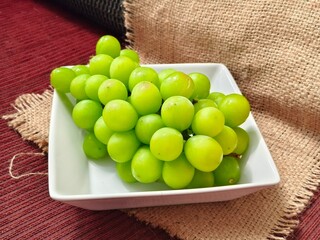 Fresh green grapes on a white plate, showcasing their juicy texture and vibrant color