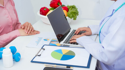 A middle aged Asian female nutritionist consults with a middle aged Asian female patient at a...