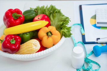 At the dining table, a nutritionist advises patients on healthy eating and weight loss. Vegetables, supplements, dumbbells, and a measuring tape are displayed, symbolizing a healthy lifestyle